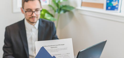 Mortgage broker and client discussing loan application with documents on table.