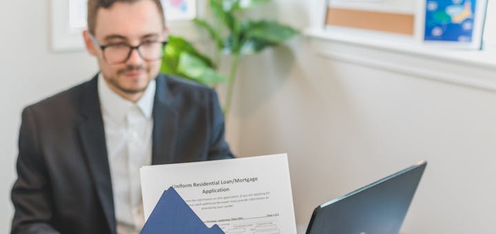 Mortgage broker and client discussing loan application with documents on table.
