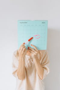 Woman holding a calendar with a date circled, conveying anticipation or planning.