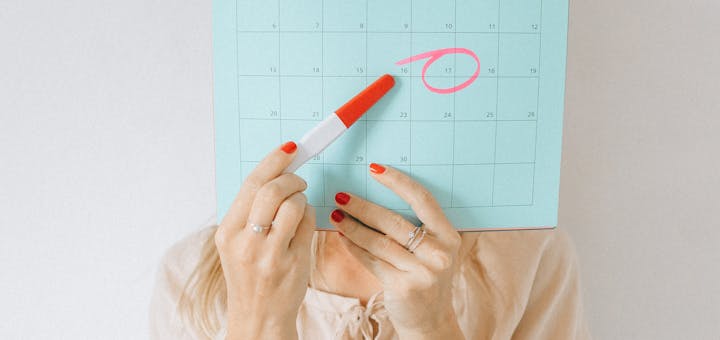 Woman holding a calendar with a date circled, conveying anticipation or planning.