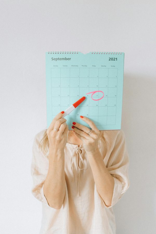 Woman holding a calendar with a date circled, conveying anticipation or planning.